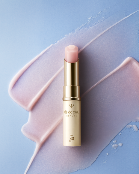 Photo of a PROTECTIVE LIP TREATMENT stick on a pastel background, showing the soft pink balm and a creamy swatch underneath.