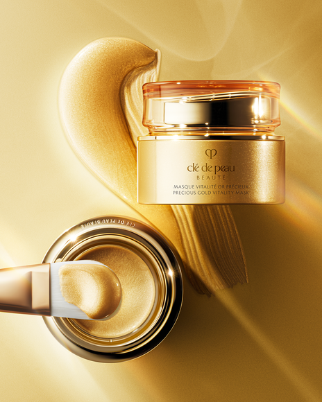 Photo of &ldquo;PRECIOUS GOLD VITALITY MASK&rdquo; &mdash; a visual showing the spread-out gold mask, a brush, and the jar container arranged together.
