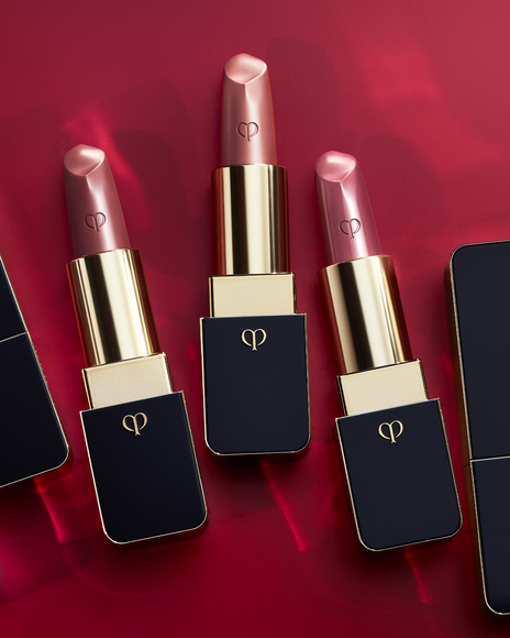 Photo of three "LIPSTICK" products arranged side by side on a red background. The caps are removed to clearly display each shade.