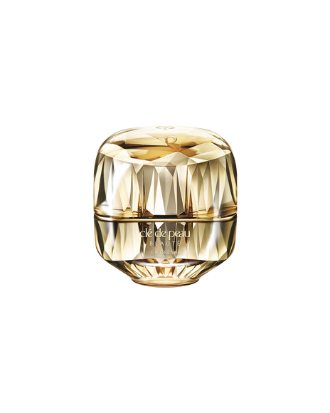 Photo of a jewel-cut, translucent gold container. The sparkling form reflects light, and the front features the brand logo and the text &ldquo;LA CR&Egrave;ME&rdquo;.
