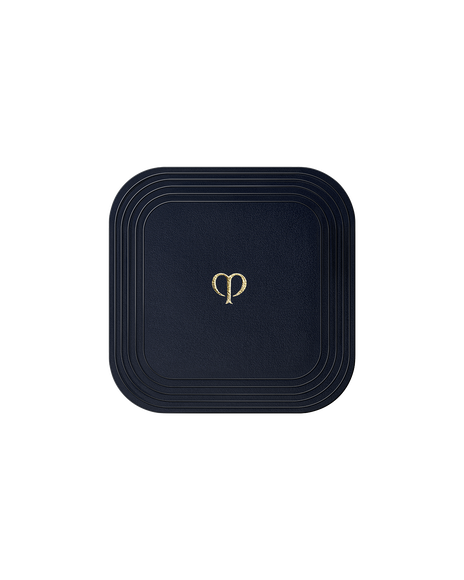 Photo of a square "PUFF (REFINING PRESSED POWDER)". It is blue-black in color, with the brand-logo engraved in gold in the center.