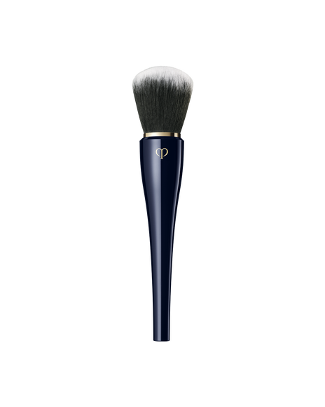 Photo of "POWDER BRUSH" with a  blue-black handle and a large, rounded bundle of bristles that spread softly. The bristles transition in color from black at the base to white at the tips.