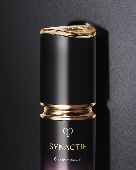 Photo of a close-up of the SYNACTIF EYE CREAM bottle with a glossy gold ring and central gold brand logo, in an elegantly finished container.