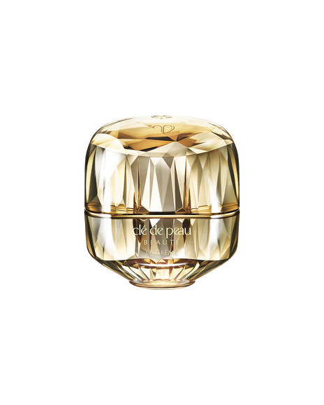 Photo of a jewel-cut, translucent gold container. The sparkling form reflects light, and the front features the brand logo and the text &ldquo;LA CR&Egrave;ME&rdquo;. 