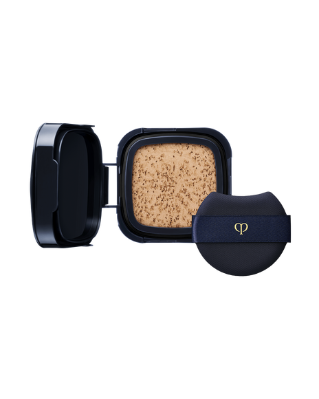 Photo of a "RADIANT CUSHION FOUNDATION DEWY (Refill)" refill case. Accompanied by a round navy puff with a gold logo. SHADE: O30