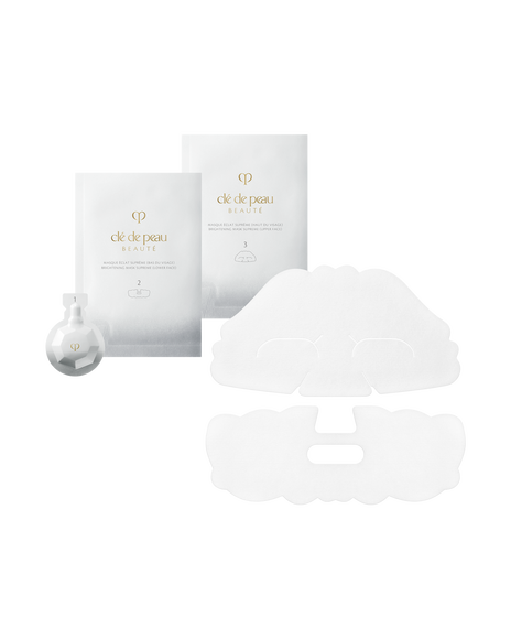 Photo of BRIGHTENING MASK TREATMENT SUPREME, showing two silver sheet mask packets for upper and lower face, a small faceted white exfoliating gel package on the left, and two unfolded white sheet masks.