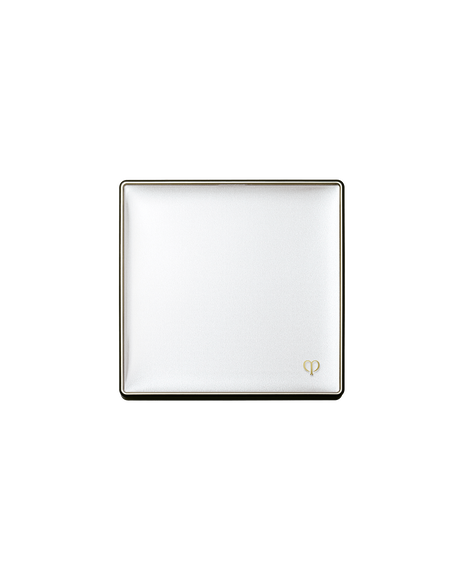Photo of a case for "BRIGHTENING POWDER FOUNDATION". The lid of the white square compact is closed with the gold brand logo engraved on it on the bottom white corner.