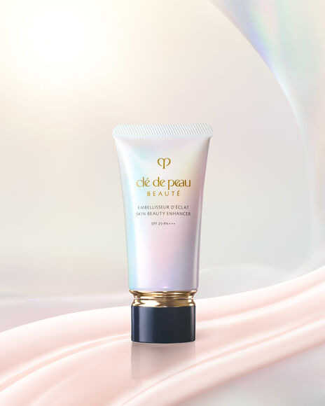 Photo of SKIN BEAUTY ENHANCER in a pearlescent gradient tube with a gold band and black cap, shown with two pale pink product swatches.Photo of SKIN BEAUTY ENHANCER in a pearlescent gradient tube with a gold band and a blue-black cap.