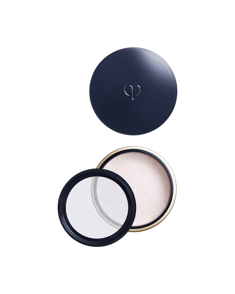 Photo of a round, blue-black and gold container with the lid on top, revealing the opened base and powder beneath. A transparent inner lid is placed on the left side. Shade: Light.
