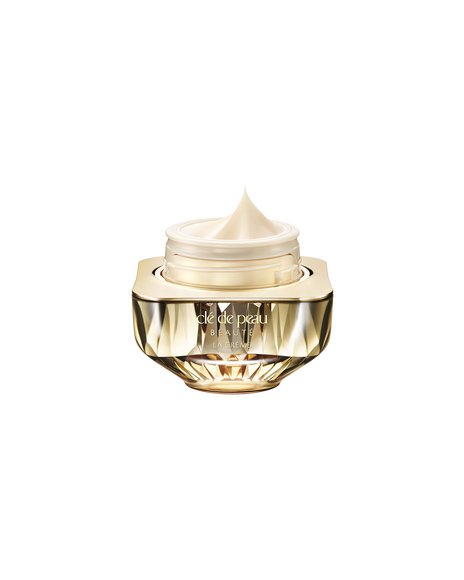 Photo of Cl&eacute; de Peau Beaut&eacute;&rsquo;s high-performance cream &ldquo;La Cr&egrave;me,&rdquo; housed in a jewel-cut, translucent gold container. The lid is open, revealing the smooth cream inside.