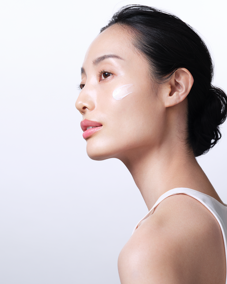 Photo of a close-up of a model with a dab of the brightening serum on her cheek.