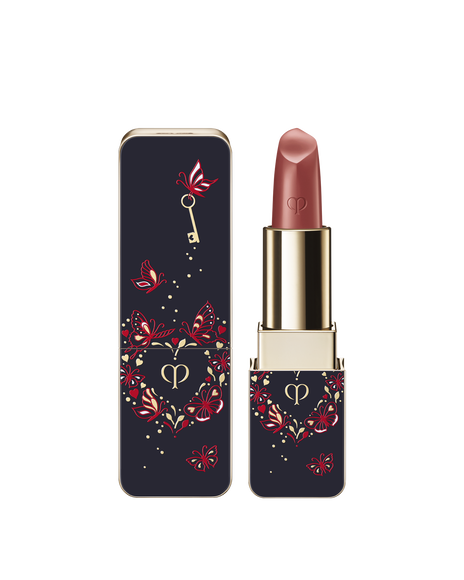 Photo of the 26 SS Collection limited-edition LIPSTICK MATTE. The navy-blue case features the Unlock Your Heart butterfly and key design, shown beside the opened lipstick. Shade: High Achiever