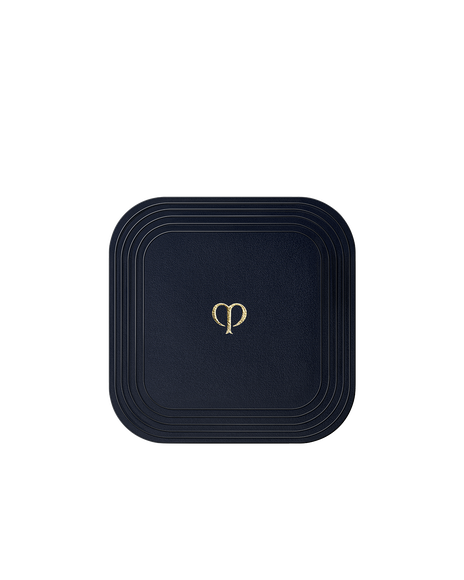 Photo of a square puff for "REFINING PRESSED POWDER", wrapped in smooth blue-black fabric.