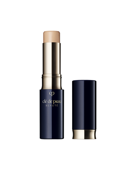 Photo of "CONCEALER," a stick-type product in a glossy blue-black and gold case. The brand logo is engraved in the center of the packaging. SHADE: Ocher.