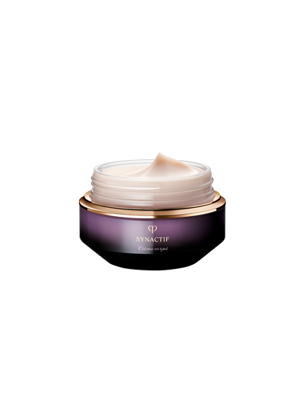 Photo of the smooth, rich, and creamy texture of SYNACTIF body cream, shown as a pale pink, glossy oval-shaped swatch against a dark violet background.