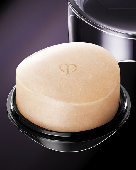 Photo of a close-up of the SYNACTIF SOAP, featuring a smooth, light pink bar with an embossed brand logo, set in a black container.