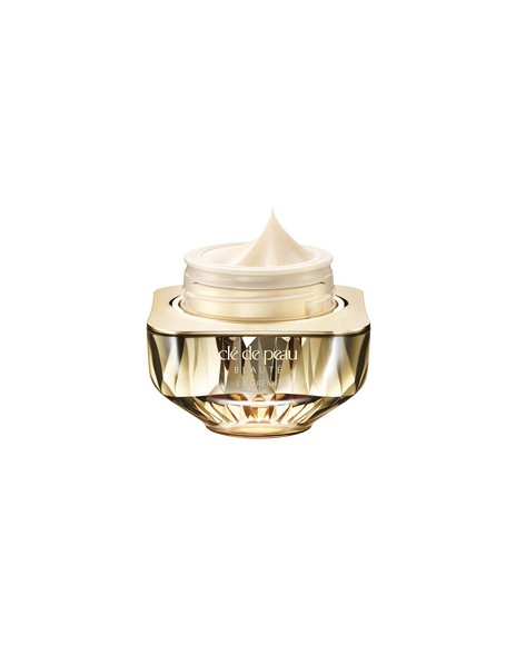 Photo of Cl&eacute; de Peau Beaut&eacute;&rsquo;s high-performance cream &ldquo;La Cr&egrave;me,&rdquo; housed in a jewel-cut, translucent gold container. The lid is open, revealing the smooth cream inside.