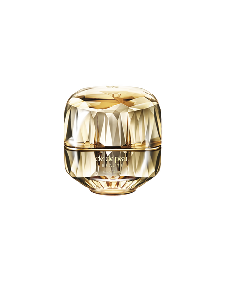 Photo of a jewel-cut, translucent gold container. The sparkling form reflects light, and the front features the brand logo and the text &ldquo;LA CR&Egrave;ME&rdquo;. 