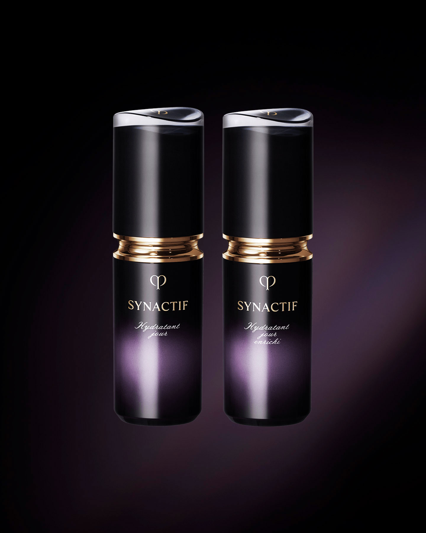 Photo of the Cl&eacute; de Peau Beaut&eacute; SYNACTIF DAYTIME MOISTURIZER (left) and DAYTIME MOISTURIZER ENRICHED (right). Both are housed in compact cylindrical bottles featuring a black-to-purple gradient. A gold accent is placed between the cap and body, and the 'SYNACTIF' logo is displayed on the front.