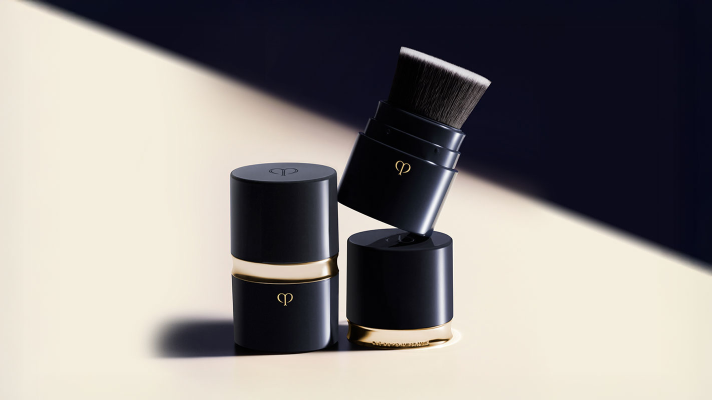 Photo of a blue-black cylindrical PORTABLE BRUSH and case with gold accents and the brand logo.