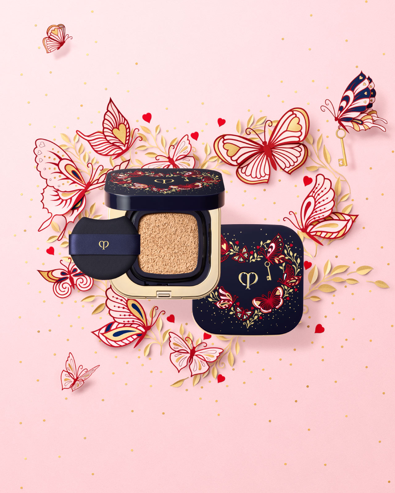 Photo of the limited-edition RADIANT CUSHION FOUNDATION DEWY IN LIMITED-EDITION COMPACT. The blue-black case features a gold heart decorated with delicate pink butterfly motifs and a small gold key.