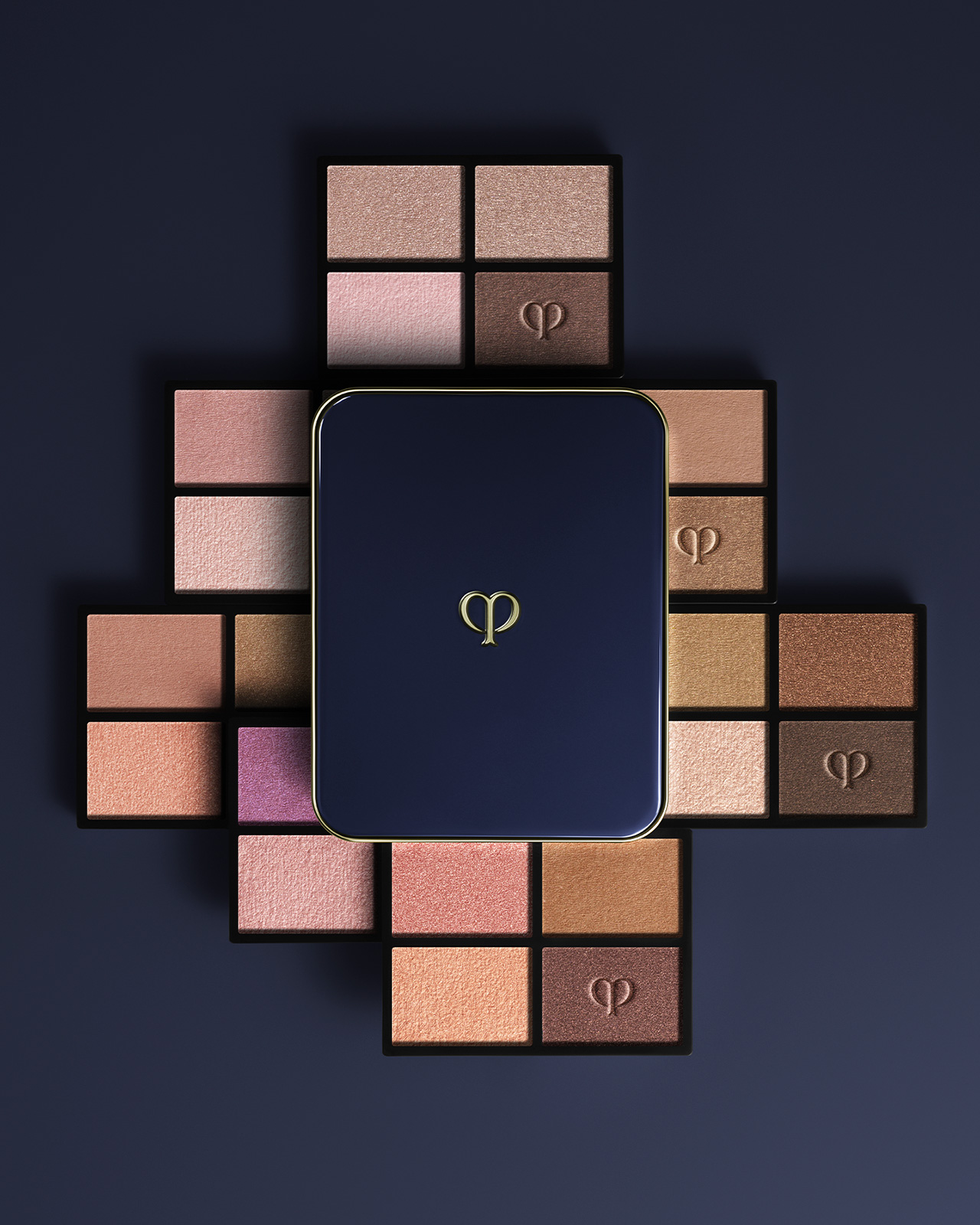 相片顯示四色眼影組合（補充裝）系列。藍黑色粉盒放在中間，棕色、粉紅色和銅色調的補充裝以放射狀形式排列。