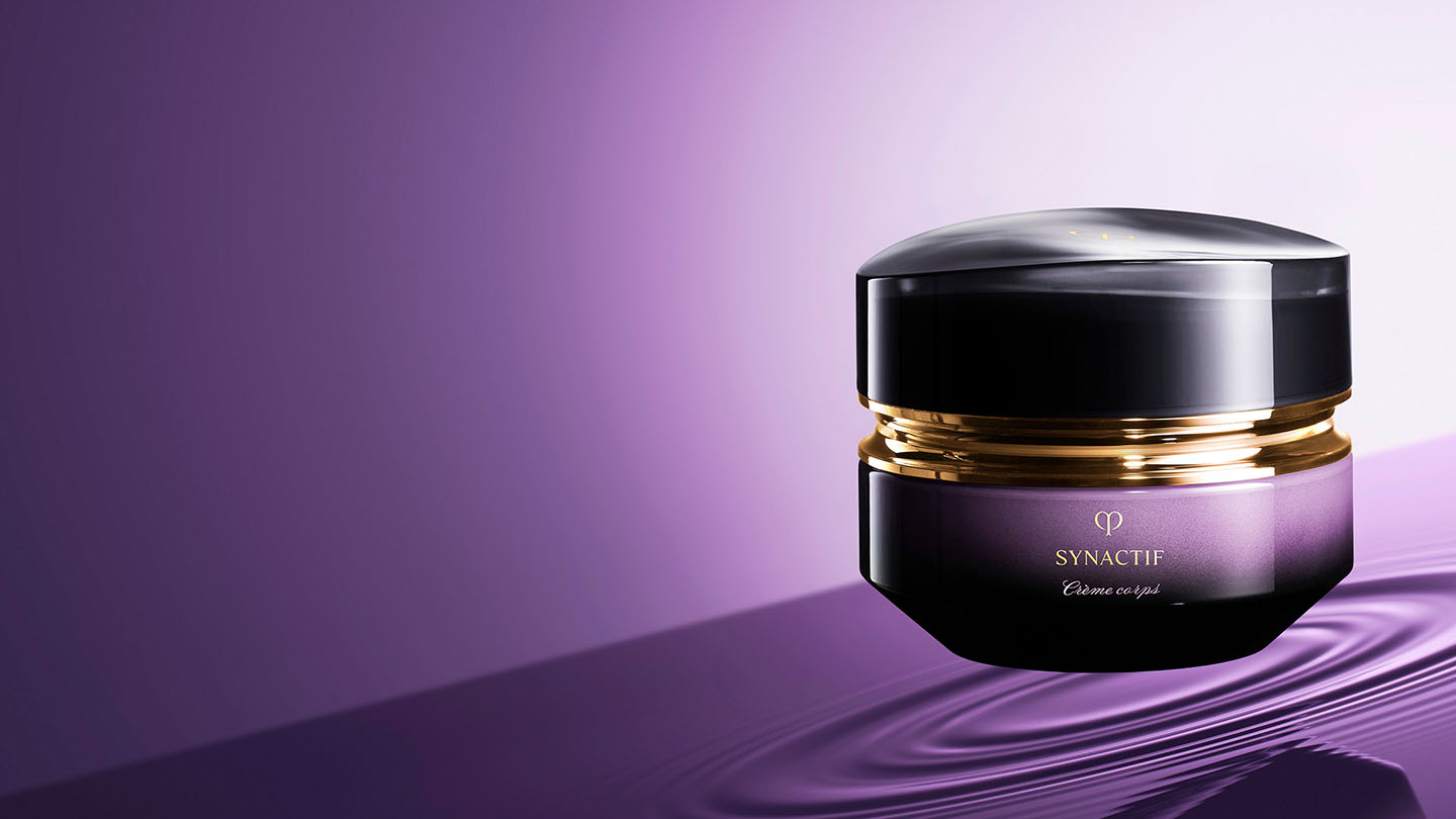 Photo of a jar of SYNACTIF body cream featuring a deep violet gradient glass body with a rounded, glossy black cap and gold accents.