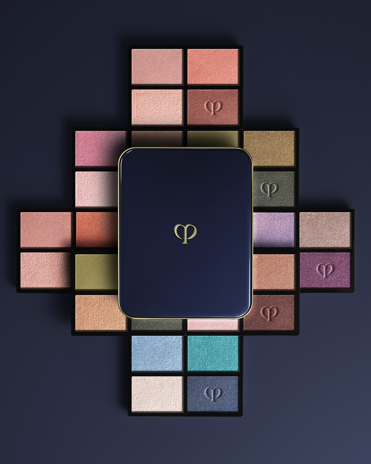 相片顯示四色眼影組合（補充裝）系列。藍黑色粉盒放在中間，粉紅色、藍色和米色調的補充裝以放射狀形式排列。