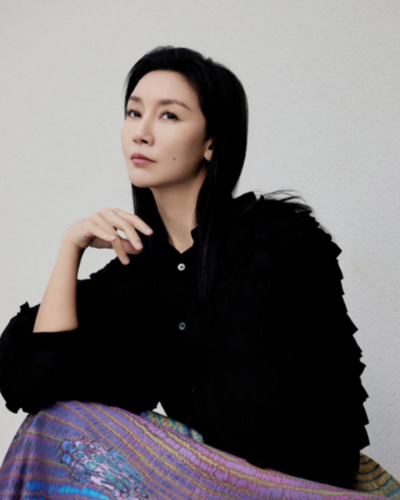 Photo of a poised Jiang Miao, the artist behind the 26SS Lunar New Year edition. Dressed in a textured black top, she rests her chin on her hand, looking directly into the camera.