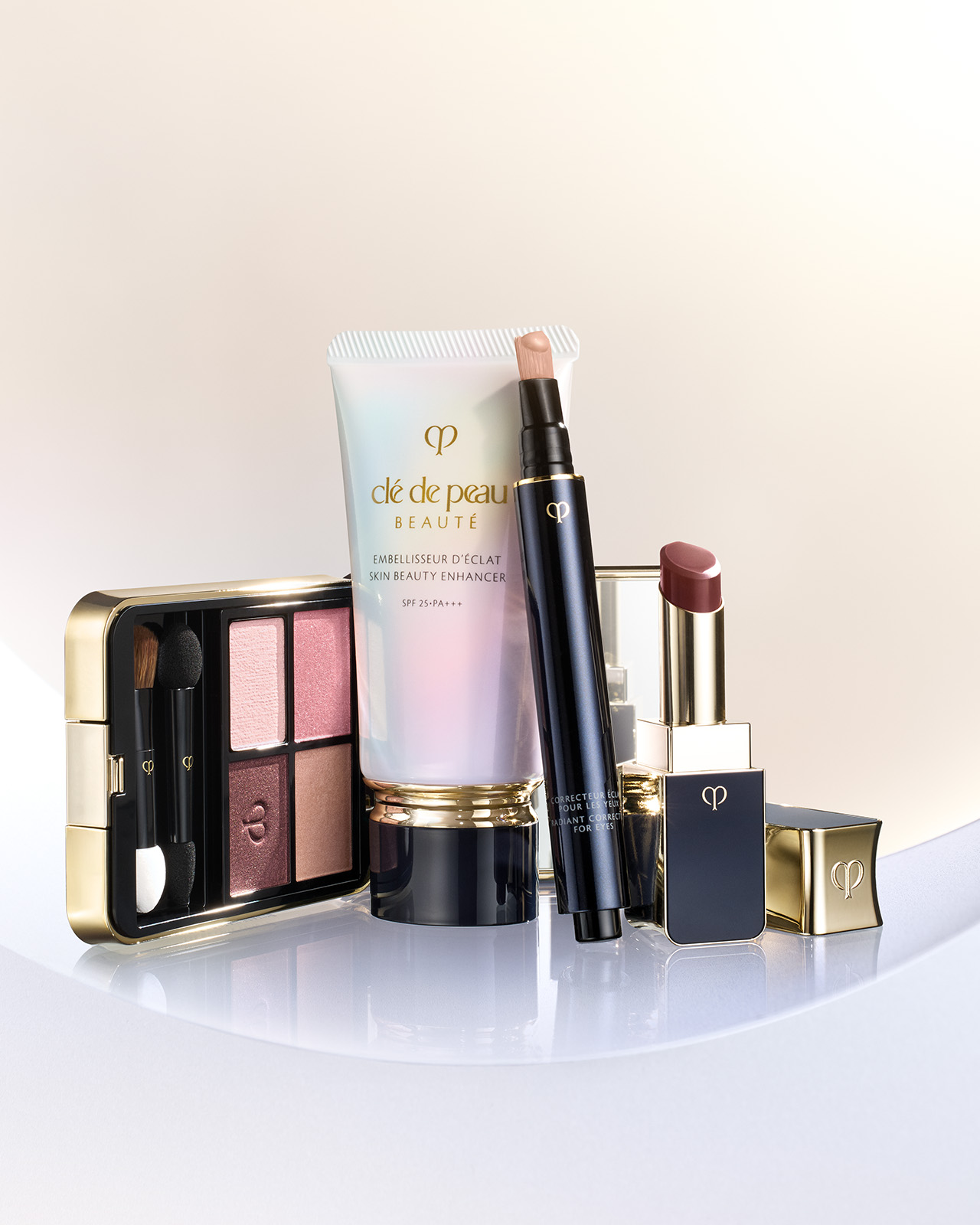 Photo of SKIN BEAUTY ENHANCER in a pearlescent gradient tube with a gold band and black cap, shown with two pale pink product swatches.