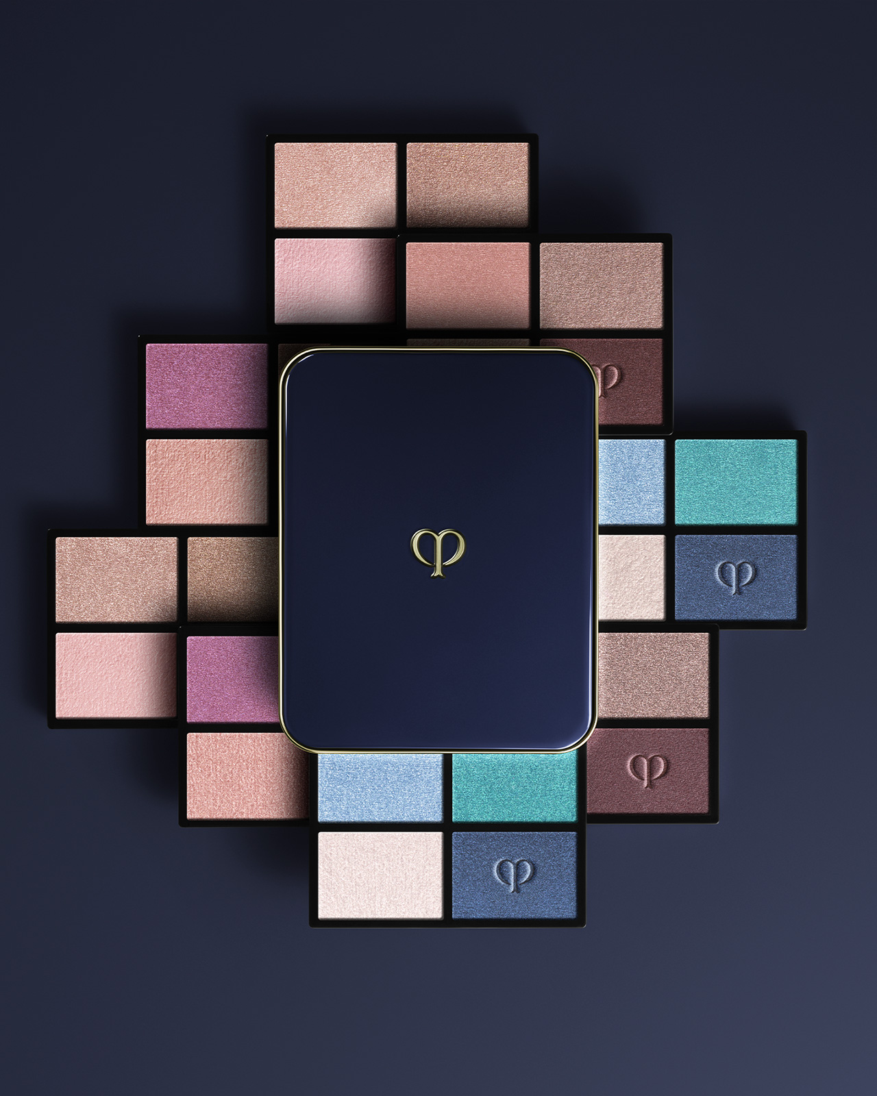 相片顯示四色眼影組合（補充裝）系列。藍黑色粉盒放在中間，米色、紫色和藍色調的補充裝以放射狀形式排列。